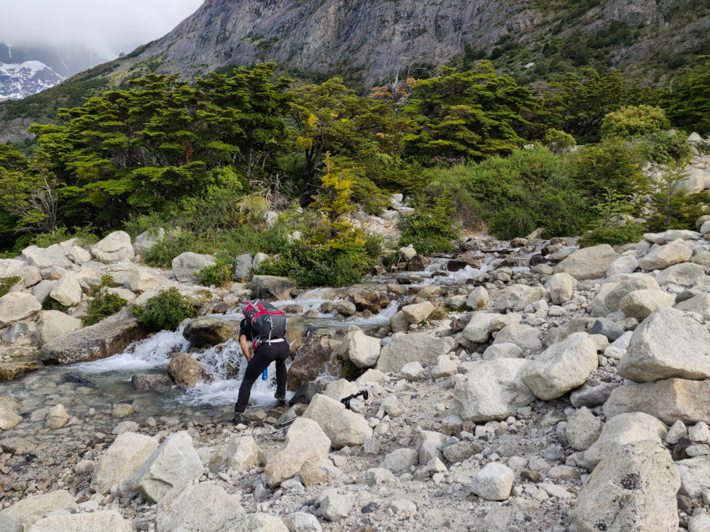 Mike filling his water from a rocky stream