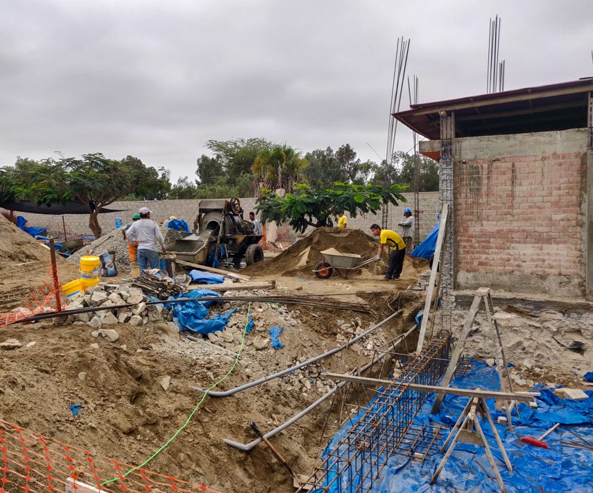 The concrete mixer, piles of materials, and crew