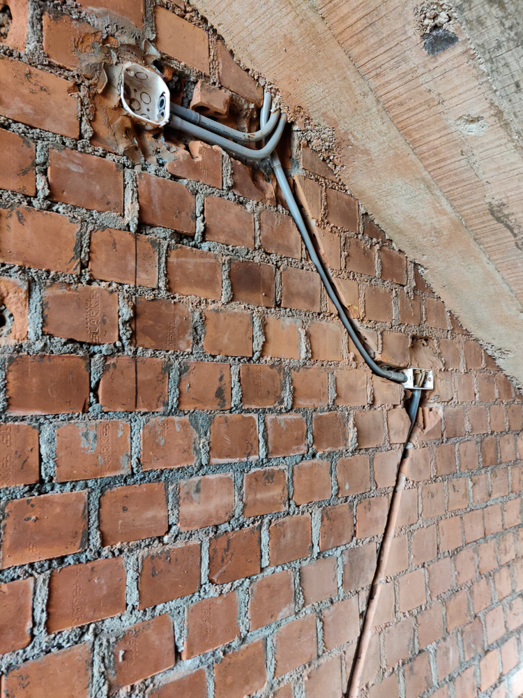 Junction boxes and conduit cut into a brick stairwell wall